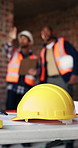 Safety, security or team with construction helmet on table for architecture or building development. Male people, contractor or civil engineering with hard hat for protection or compliance on site