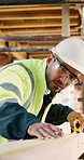 Construction, measurement and man with wood at site for accuracy, renovation and building project. Architecture, contractor and person with tape measure for dimensions, distance and infrastructure