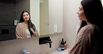 Mirror, beauty and woman brushing hair in bathroom for grooming, self care or morning routine. Happy, reflection and Asian female person with hairstyle for daily haircare treatment in apartment.