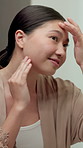 Skincare, check and Asian woman in mirror in bathroom for wellness, healthy skin and grooming. Reflection, home and happy person with face inspection for beauty, dermatology and results for glow