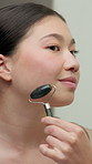Bathroom, skincare or woman with jade roller in house, lymphatic drainage or blood circulation massage. Grooming, beauty tool or asian person with facial treatment, wellness or anti aging benefits
