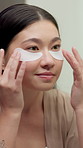 Mirror, skincare and Asian woman with eye mask for dark circles, collagen and facial treatment. Bathroom, reflection and person with pads, cosmetics and wellness for hydration, anti aging and beauty