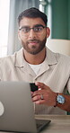 Face, laptop and phone with man in home office for planning, remote work or research. App, computer and smile of freelance employee at desk in apartment for agenda, digital feedback or schedule