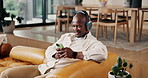 Headphones, dance and black man with phone on couch for online radio, listening and weekend playlist. Smile, audio tech and person with music app subscription for streaming, home and moving to beat