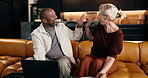 High five, laptop and paper with interracial couple on sofa in home living room for budget success. Computer, finance and paperwork with mature people in apartment for celebration of investment goals