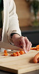 Hands, cooking and person with carrot on chopping board for healthy diet, wellness or nutrition. Cut vegetables, woman and meal prep with knife at home, organic ingredients and vegan food in kitchen