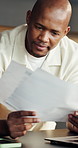 Man, reading and documents in home with laptop, financial planning and info for income tax preparation. Black person, review paperwork and computer in house with audit, budget and wealth management.