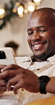 Man, laughing and texting with phone, house and communication with contact on social media and chat. Typing, online and black person with mobile, networking and reading funny message on web in lounge