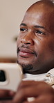 Man, thinking and texting with phone, house and communication with contact on social media and chat. Typing, online and black person with mobile, reflection and reading message on website in lounge