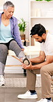 Mature, woman and physiotherapist in clinic with foot pain, rehabilitation and medical assistance. Person, ankle injury and orthopedic worker in consultation with help, healing or healthcare support.