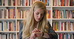 Woman, student and smart watch in library at college with typing by bookshelf, education or reminder at campus. Girl, wristwatch and iot clock for learning, research and application at university