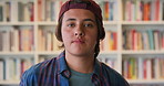 Serious, bookshelf and face of teenager in library for high school, education or studying with knowledge. Academy, portrait and boy student with confidence for learn, pride and opportunity on campus.