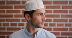 Education, face and thinking with Muslim man on brick wall background at college campus. Belief, faith and learning with serious student at university for Arabic, Islamic or religious study as pupil