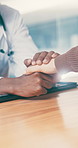 Healthcare, holding hands and support with doctor comforting patient in hospital for diagnosis. Empathy, flare and help with medical professional consoling person at table in clinic for wellness
