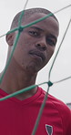 Soccer, face and black man by net on field for playing game, training or practice for match. Athlete, player and portrait of serious person by goalpost for exercise, challenge and fitness outdoor