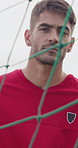 Soccer, face and man by net on field for playing game, training and practice for match. Athlete, goalkeeper and portrait of serious person by goalpost for exercise, challenge and fitness outdoor