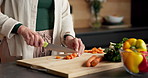 Cutting, hands and vegetables with person in kitchen of home for healthy meal preparation. Cooking, food and knife with senior woman at counter in apartment for cuisine, culinary hobby or recipe
