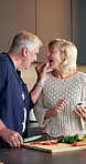 Vegetables, cooking and old couple with phone, feeding and laugh with organic recipe in kitchen. Mobile, meal prep and senior people with chopping board, eating and funny with online blog at home