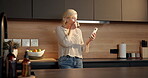 Coffee, drink or old woman with mobile in kitchen, reading funny message or check app for notification. Laugh, happy or senior person with phone for browsing internet, tea cup or social media in home