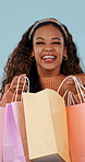 Smile, excited and woman with bags, shopping and client with retail on blue studio background. Surprise, happy person or consumer with luxury clothes, discount deal and expensive items with wow