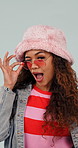 Face, sunglasses and woman with wink, happiness and facial expression on white studio background. Designer shades, funky eyewear and person with fashion, stylish clothes and cool with trendy outfit