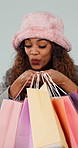 Happy, excited and woman with bags, shopping and client with retail on blue studio background. Surprise, person and client with excitement, luxury clothes and expensive items with wow and discount