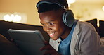 Gaming, headphones and child with tablet in lounge, virtual competition and excited for win at night. Gamer, success and playing video game with tech in evening, fist pump and black kid in house