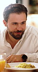 Talking, food and man in home with breakfast in morning for conversation, nutrition or chatting. Happy, orange juice and male person in discussion with eggs for health, wellness or meal in apartment.
