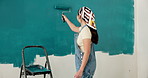 Back, painting and woman at house with wall, interior design and diy project for renovation. Painter, female person and paintbrush in home for remodeling, property makeover and household improvement