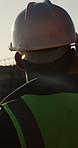 Construction site, architect and man with helmet for safety, thinking and infrastructure development. Engineer, ppe or black person outdoor for planning, project or building inspection with back view