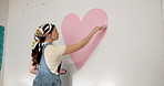 Woman, heart or interior art with paint on wall for nursery, love or fun activity for home decor. Female person, painter or shape with romantic gesture or symbol for mural design or style in house