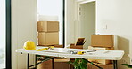 Boxes, diy and tools on table in home for improvement, maintenance or renovation project. Hard hat, level and measuring tape in room interior for construction, property development or real estate