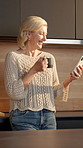 Coffee, woman and laugh with phone in home for internet meme, funny online video and streaming. Beverage, mature person and happy with mobile in kitchen for reading comic status, social media or joke