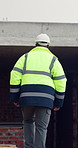 Walking, inspection and back of person for construction site, quality assurance and building project. Architecture, contractor and worker with ppe for engineering, safety compliance or infrastructure
