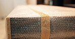 Bubble wrap, packaging and shipping with box for safety, delivery service and logistics in empty office. Fragile goods, distribution and tape for protection, plastic safeguarding and supply chain