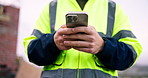 Man, phone and hands of construction worker on site with texting, communication or email for feedback. Technology, typing and male civil engineer with cellphone for chatting with building approval.