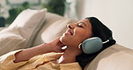 Headphones, relax and woman on sofa with singing to music, playlist or radio online in home. Happy, audio tech and female person chilling with streaming of album on weekend in living room at house.
