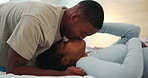 Love, couple and kiss in bedroom with connection, happiness and loyalty together at home. Smile, man and African woman in bed with romance for affection, trust and healthy relationship with partner