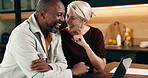 Mature, couple and holding hands in house with laptop, laugh and funny discussion for booking holiday. Happy, interracial marriage and people in home with computer, joke and research for vacation.