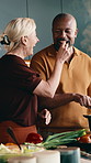 Cooking, feed and smile of interracial couple in kitchen together for diet or healthy eating. Food, ingredients and taste with mature people at counter in apartment for meal preparation or nutrition