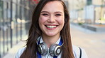 Face, businesswoman and travel in city with smile, headphones and experience for marketing career. Happy, female person and audio tech downtown with pride, good mood and commute for advertising job.