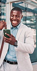 Fist pump, phone and black man in glass office with winning, capital gain or approval on investment. Excited, cellphone and financial manager with celebration for finance achievement in workplace.