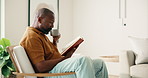 Relax, black man and reading book in home with coffee, calm or literature on weekend in morning. Novel, drink or mature person on armchair at living room with story, information or knowledge hobby