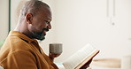 Laugh, black man and reading book in home with tea, relax and literature on weekend in morning. Novel, drink or mature person at living room apartment with funny story, information or happiness