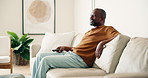 Man, laugh and watching tv in living room with remote, relax or joke for comedy show on weekend break. Mature, black person and change channel in home with tech, streaming funny film or entertainment