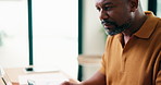 Laptop, reading and black man in home with remote work, creativity and check article for blog post. Happy, mature person or freelance writer in house with computer, plan or review project for website