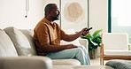 Man, relax and watching tv in home with remote, sports game or football contest on weekend break. Happy, mature black person and change channel in living room with tech, suspense or soccer broadcast.