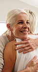 Mature, women and hug in house for welcome, bonding and connection in living room with a smile. Friends, people or sisterhood for visit, care and love with conversation of gratitude for relationship