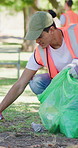 Volunteer, man and cleaning litter in park with trash bag, non profit project and social responsibility. Person, pick up garbage or charity team outdoor with recycling, sustainability or conservation
