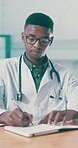 Glasses, healthcare and writing with doctor black man in hospital for agenda, report or schedule. Notebook, pen and review with serious medical professional at desk in clinic for appointment calendar